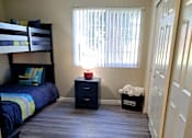 Thumbnail 12 of 36 - A room with a bunk bed, a nightstand, and a dresser at Raintree Apartments, CA 92346