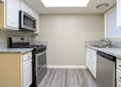 Thumbnail 20 of 36 - A kitchen with a black microwave above a black stove at Raintree Apartments, CA 92346