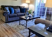 Thumbnail 3 of 36 - A living room with a blue couch and a coffee table at Raintree Apartments, CA 92346