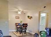Thumbnail 5 of 36 - A living room with a dining table and chairs at Raintree Apartments, CA 92346