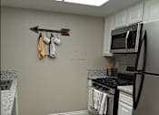 Thumbnail 8 of 36 - A kitchen with a black stove top oven and a black refrigerator at Raintree Apartments, CA 92346