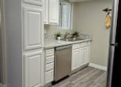 Thumbnail 9 of 36 - A kitchen with white cabinets and a stainless steel refrigerator at Raintree Apartments, CA 92346