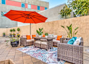 Thumbnail 7 of 20 - a patio with wicker furniture and an orange umbrella