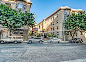 Thumbnail 1 of 20 - a city street with cars parked on the side of the road and a building in the background