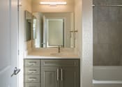 Thumbnail 18 of 19 - A bathroom with a sink, mirror, and bathtub.
