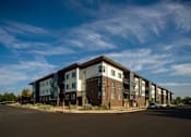 Thumbnail 2 of 24 - Apartment complex with a car parked in front.