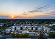 Thumbnail 5 of 24 - A sunset view of a town with a large building in the foreground.