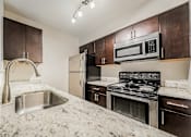 Thumbnail 25 of 36 - A kitchen with a sink, stove, and refrigerator.