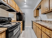 Thumbnail 28 of 36 - Galley kitchen with light wood cabinetry.
