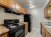 Thumbnail 29 of 36 - A kitchen with a black stove and refrigerator.