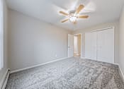 Thumbnail 30 of 36 - A room with a ceiling fan and carpeted floor.