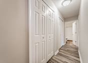 Thumbnail 26 of 36 - A hallway with white doors and wooden floors.