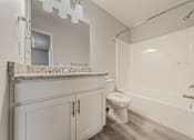 Thumbnail 9 of 36 - Updated townhome bathroom with granite countertop and white tub.