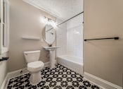 Thumbnail 26 of 39 - A bathroom with a toilet, sink, and a clock on the wall.