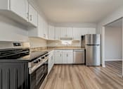 Thumbnail 2 of 32 - A kitchen with a black stove top oven and white cabinets.
