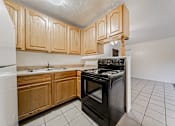 Thumbnail 14 of 23 - A kitchen with wooden cabinets and a black oven.