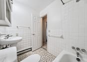Thumbnail 9 of 23 - A white bathroom with a toilet, sink, and bathtub.