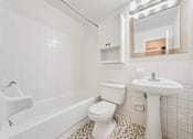Thumbnail 8 of 23 - A white bathroom with a toilet, sink, and bathtub.