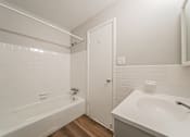 Thumbnail 27 of 32 - A white bathroom with a tub, sink and mirror.
