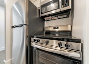 Thumbnail 26 of 29 - A modern kitchen with a stainless steel refrigerator and oven.