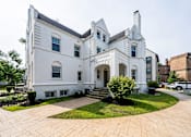 Thumbnail 22 of 23 - A white two-story house with a black roof and a grey roof.