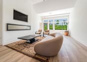 Thumbnail 35 of 39 - A modern living room with a brown chair and a black coffee table.