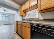 Thumbnail 13 of 21 - A kitchen with wooden cabinets and a black dishwasher at Integrity Chardon Apartments, Chardon,  Ohio