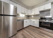Thumbnail 4 of 32 - A modern kitchen with a stainless steel refrigerator and oven.