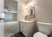 Thumbnail 13 of 32 - A bathroom with a toilet, sink, and mirror.