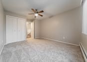 Thumbnail 14 of 32 - A room with a ceiling fan and carpeted floor.