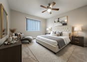 Thumbnail 9 of 32 - A bedroom with a large bed, a ceiling fan, and a nightstand with a lamp.
