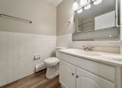 Thumbnail 16 of 32 - A white toilet sits next to a white sink in a bathroom.