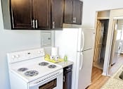 Thumbnail 34 of 49 - A white stove and refrigerator in a kitchen with wood floors and dark brown cabinets. at Integrity Berea Apartments, Berea, OH, 44017