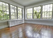 Thumbnail 9 of 39 - A room with a wooden floor and three windows at Integrity Gold Coast Apartments, Ohio, 44102