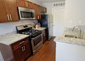 Thumbnail 10 of 36 - Townhome kitchen peninsula with granite counters, stainless steel appliances, and hardwood flooring.