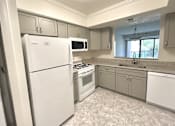 Thumbnail 14 of 42 - A kitchen with white appliances and grey cabinets.at Atrium in The Village, Beachwood, OH 44122