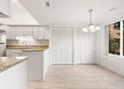Thumbnail 10 of 42 - A kitchen with white cabinets and a granite countertop with a dining area.at Atrium in The Village, Beachwood Ohio