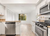 Thumbnail 9 of 42 - A kitchen with white cabinets and stainless steel appliances.at Atrium in The Village, Beachwood
