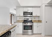 Thumbnail 8 of 42 - A kitchen with a granite countertop and stainless steel appliances.at Atrium in The Village, Ohio, 44122