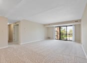 Thumbnail 18 of 42 - A large living room with a carpeted floor and sliding glass doors leading to a balcony.at Atrium in The Village, Beachwood Ohio