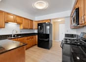 Thumbnail 11 of 42 - A kitchen with black appliances and wooden cabinets.at Atrium in The Village, Beachwood, 44122