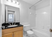 Thumbnail 9 of 15 - White bathroom with oak cabinet and black counter at Integrity Medina Apartments,  Ohio, 44256