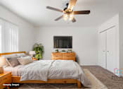 Thumbnail 24 of 32 - A bedroom with a bed, dresser, and ceiling fan.