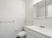 Thumbnail 28 of 32 - Updated Wynwood bathroom with white cabinets, counters, and tiling.