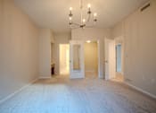 Thumbnail 30 of 42 - A large empty room with a chandelier and two doors.