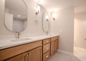 Thumbnail 31 of 42 - A bathroom with a white counter top and wooden cabinets.