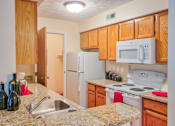 Thumbnail 7 of 46 - Traditional kitchen with white appliances and wood cabinetry at Hunt Club Apartments, Copley, 44321