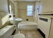 Thumbnail 31 of 35 - Tiled bathroom with white tub and standing sink.