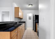 Thumbnail 11 of 22 - A kitchen with black countertops and wooden cabinets at Integrity Medina Apartments, Medina, OH,  44256