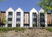 Thumbnail 5 of 29 - A row of white houses with black shutters and a stone wall in front.